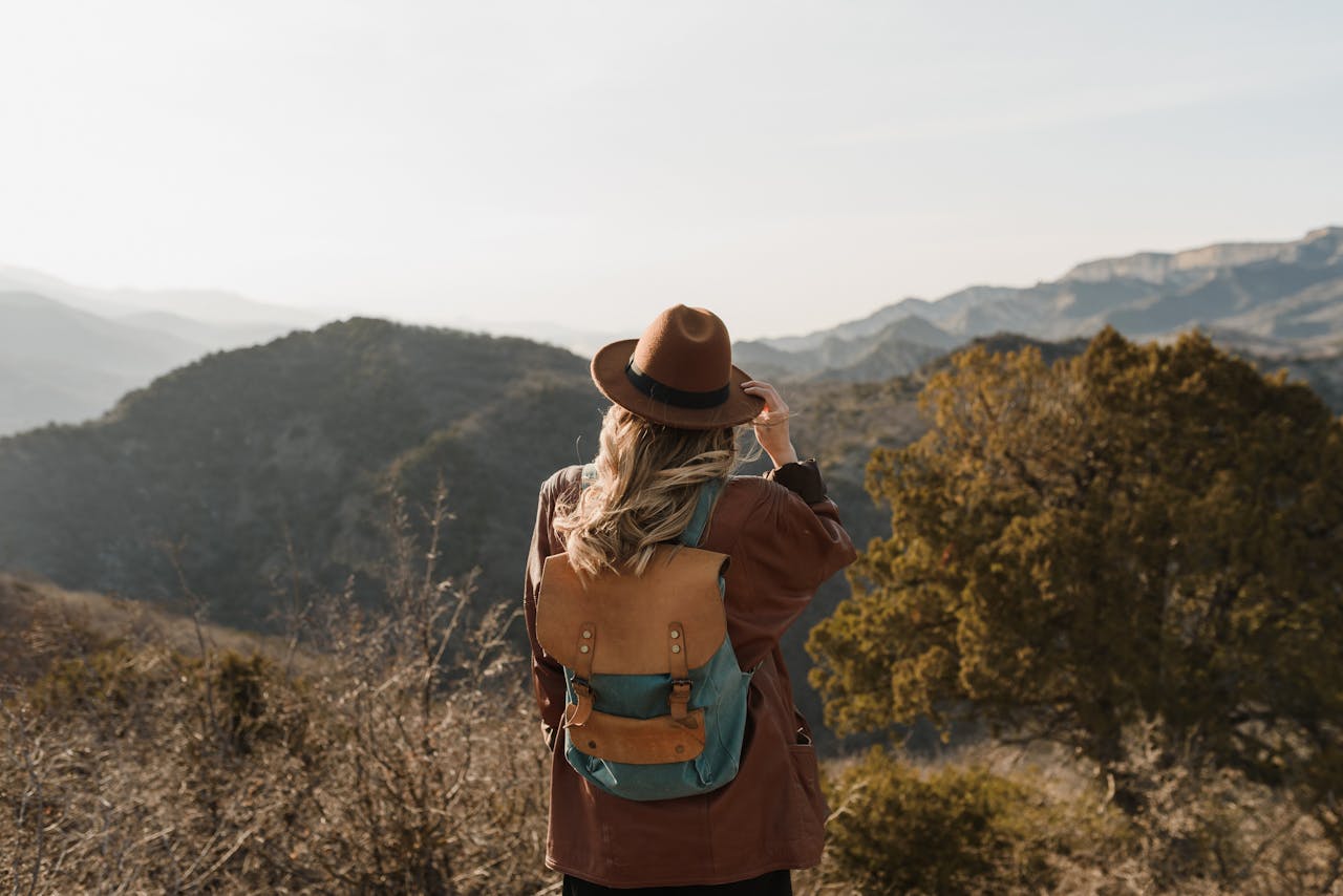 discover Woman wearing a backpack hiking in mountainous countryside, enjoying the scenic view.